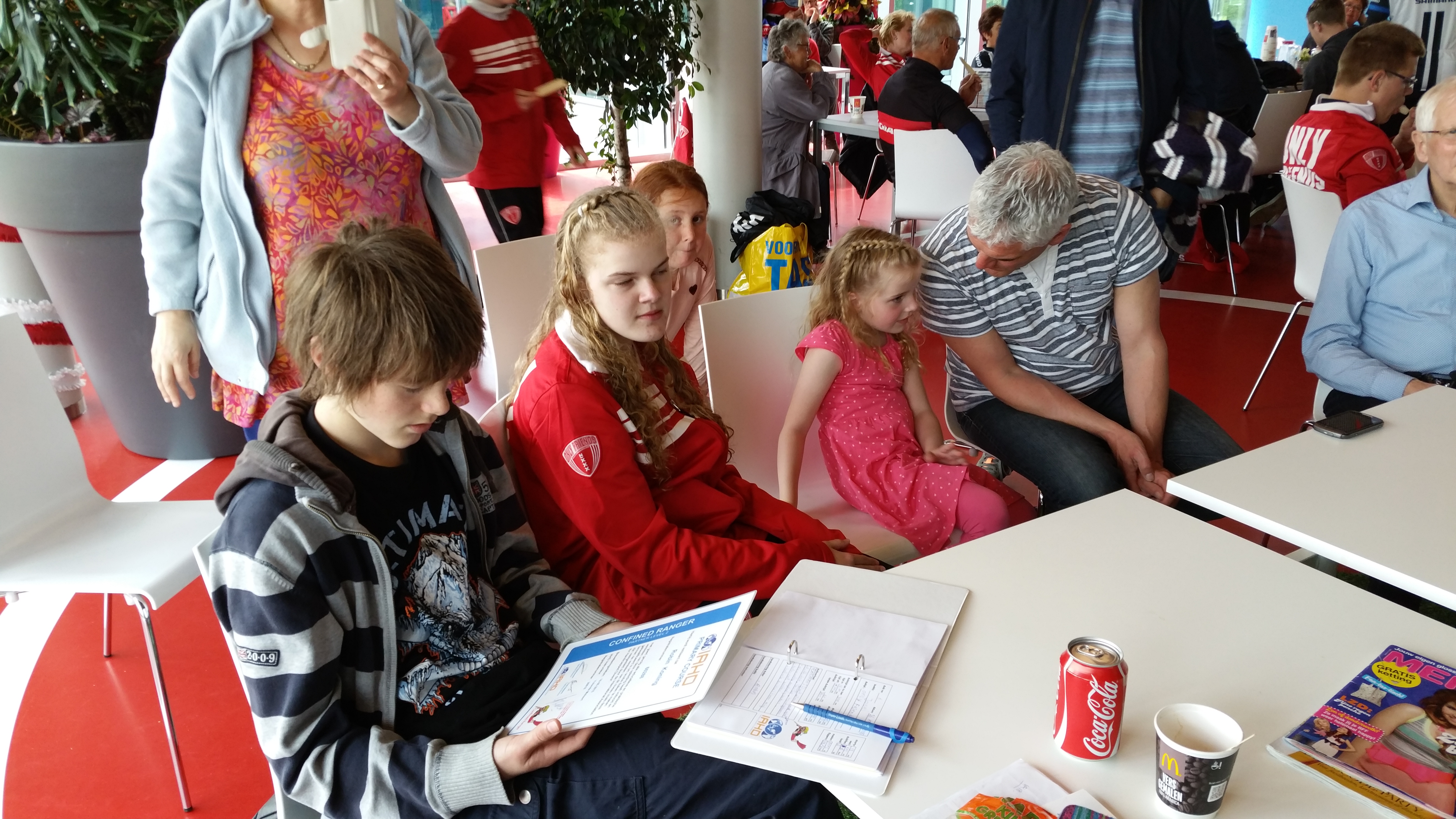 Kids kijken naar hun brevet met trotse ouders en opa's/oma's om hen heen